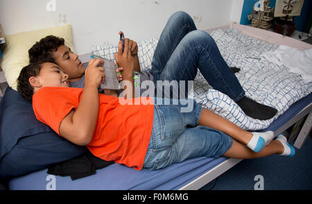 Zwei Brüder, die auf ihre Spiele-Konsolen drinnen spielen Stockfoto