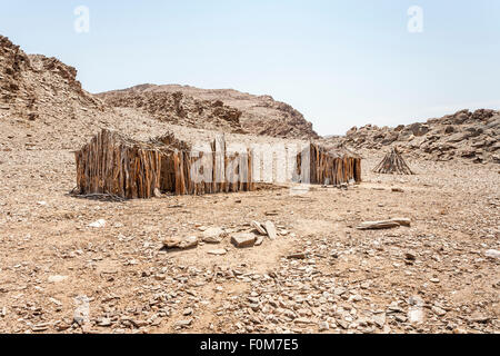 Angolanische Landschaft und Lebensstil: aufgegeben Holzrahmen von primitiven Lehmhütten in trockenen Wüstenlandschaft, südlichen Angola nahe der Grenze zu Namibia Stockfoto