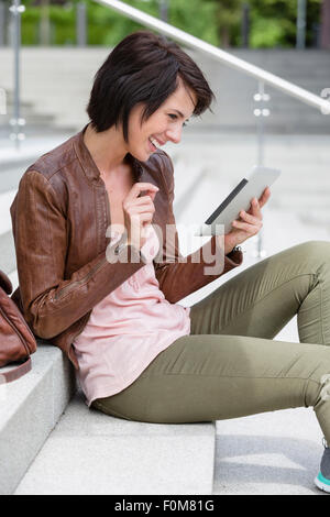 Frau sitzt auf der Treppe und ein Tablet-PC verwenden Stockfoto