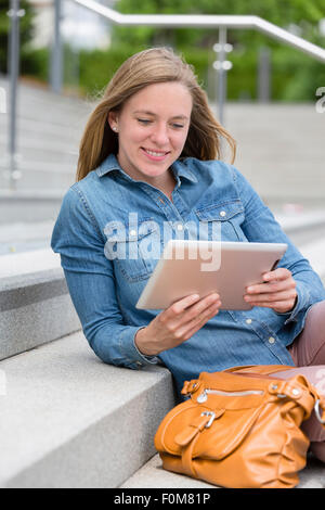 Frau sitzt auf der Treppe und ein Tablet-PC verwenden Stockfoto