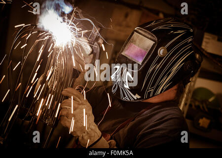 Schweißer, Gesichtsmaske und Schutzhandschuhe tragen, in Fabrik Stockfoto