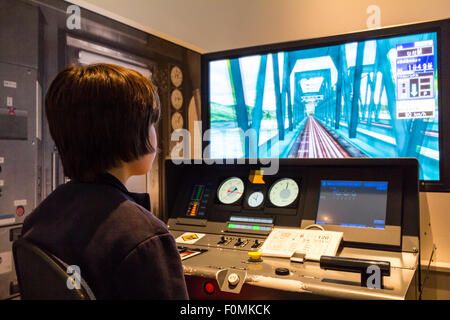 Shinkansen Museum, Nagoya. Blick über die Schulter der Kaukasischen junge Kind 10-12 Jahre alte, sitzen im Control Panel und ein Bildschirm in Train Simulator. Stockfoto