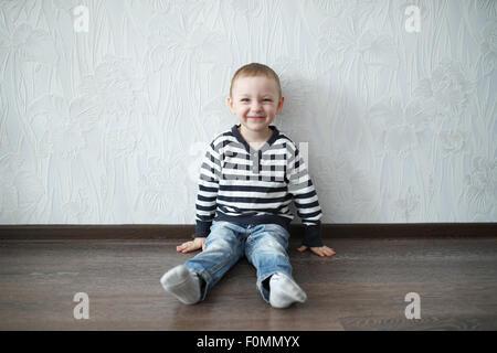 kleiner Junge auf dem Boden sitzend Stockfoto