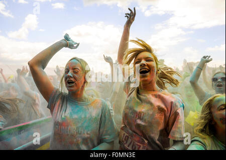 Junge Frauen springen und singen und bedeckt mit farbigen Pulver bei Run oder Dye 5k laufen Stockfoto