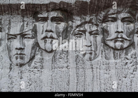 Stein geschnitzte Gesichter auf weißen Marmorfelsen mit Anzeichen des Alterns Stockfoto