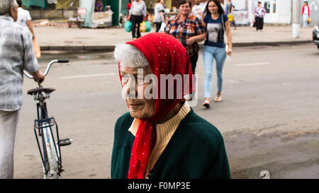 Ältere Frau in einem roten Kopf Schal Spaziergänge entlang einer Fußgängerzone Stockfoto