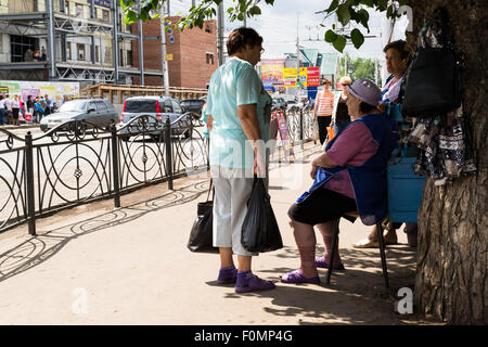 Drei Frauen sprechen auf eine russische Straße Ecke Schutz vor der heißen Sonne overhead Stockfoto
