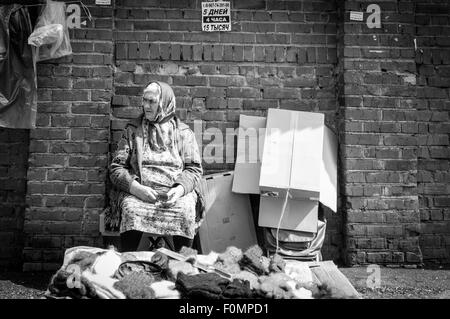 Alten Rentner Markt Händler wartet auf Käufer zum Kauf gesponnene Wolle Handschuhe und Socken Stockfoto