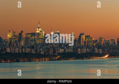 Der Himmel leuchtet Orange über die Skyline von Manhattan und den Hudson Fluss kurz nach Sonnenuntergang in New York City. Stockfoto