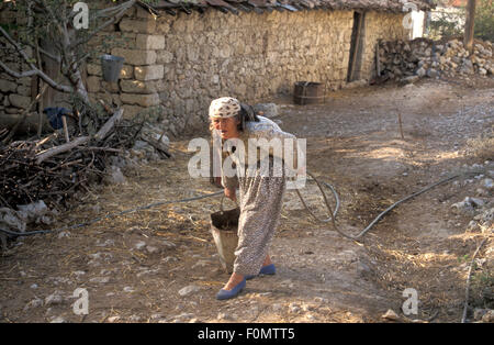 Türkische Seniorin, die Wasser aus einem Brunnen in der ländlichen Türkei sammeln Stockfoto
