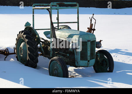 Am alten klassischen Traktor stehen im Schnee für den Frühling warten. Stockfoto