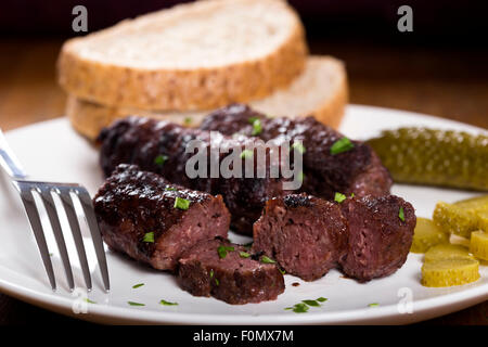 Traditionelles Essen "Mici" Würzige Frikadellen auf Teller mit sauren Gurken Scheiben Stockfoto