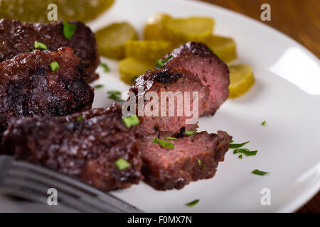 Traditionelles Essen "Mici" Würzige Frikadellen auf Teller mit sauren Gurken Scheiben Stockfoto