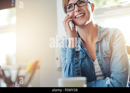 Close up Junge Büro Frau mit jemand sprechen auf ihrem Mobiltelefon, während sie in die Ferne mit glücklichen Gesichtsausdruck. Stockfoto