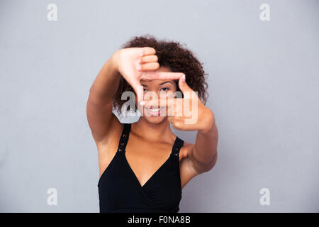 Porträt einer glücklich afrikanische Frau, Blick in die Kamera durch Frame Geste isoliert auf weißem Hintergrund Stockfoto