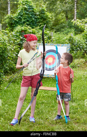 Mädchen und Jungen mit Bogen in der Nähe von Sport Ziel im sonnigen Sommertag Stockfoto