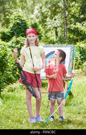 Mädchen und Jungen mit Bogen in der Nähe von Sport Ziel im sonnigen Sommertag Stockfoto