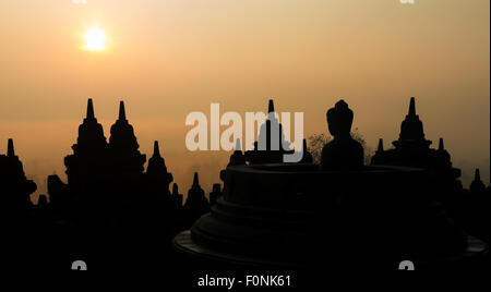 Silhouetten von einer Buddha-Statue auf der Unesco-Weltkulturerbe Website des Borobudur-Tempel in der Morgendämmerung auf der Insel Java, Indonesien, Asien. Stockfoto