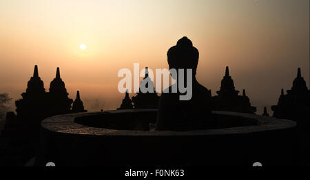 Silhouetten von einer Buddha-Statue auf der Unesco-Weltkulturerbe Website des Borobudur-Tempel in der Morgendämmerung auf der Insel Java, Indonesien, Asien. Stockfoto