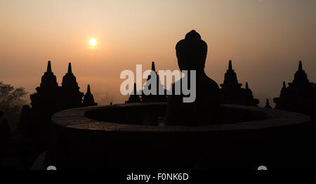 Panorama einer Silhouette einer Buddha-Statue auf der Unesco-Weltkulturerbe Website des Borobudur-Tempel in der Morgendämmerung auf der Insel Java, Indonesien, Asien. Stockfoto