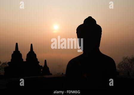 Silhouetten von einer Buddha-Statue auf der Unesco-Weltkulturerbe Website des Borobudur-Tempel in der Morgendämmerung auf der Insel Java, Indonesien, Asien. Stockfoto