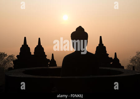 Silhouetten von einer Buddha-Statue auf der Unesco-Weltkulturerbe Website des Borobudur-Tempel in der Morgendämmerung auf der Insel Java, Indonesien, Asien. Stockfoto