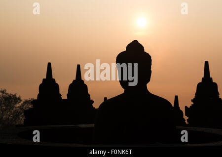 Silhouetten von einer Buddha-Statue auf der Unesco-Weltkulturerbe Website des Borobudur-Tempel in der Morgendämmerung auf der Insel Java, Indonesien, Asien. Stockfoto