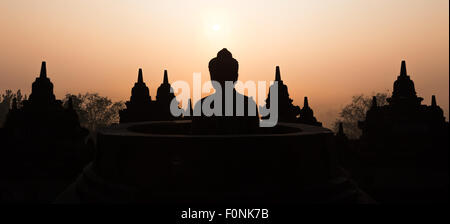 Panorama von Silhouetten einer Buddha-Statue auf der Unesco-Weltkulturerbe Website des Borobudur-Tempel in der Morgendämmerung auf der Insel Java, Indonesien, Asien. Stockfoto