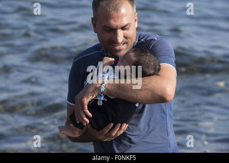 Lesbos, Griechenland. 19. August 2015. Ein syrischer Flüchtling hält ein Neugeborenes nach der Landung an einem Strand auf der Nordseite der Insel Lesbos. Mehr als 120.000 Flüchtlingen und Migranten haben aus der Türkei nach Griechenland bis Ende Juli 2015, nach des UN-Flüchtlingshilfswerks gekreuzt. Bildnachweis: Nikolas Georgiou/ZUMA Draht/Alamy Live-Nachrichten Stockfoto