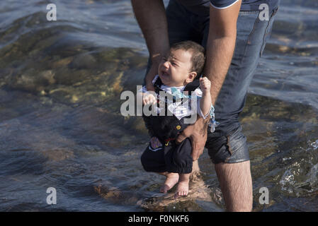 Lesbos, Griechenland. 19. August 2015. Ein syrischer Flüchtling hält ein Neugeborenes nach der Landung an einem Strand auf der Nordseite der Insel Lesbos. Mehr als 120.000 Flüchtlingen und Migranten haben aus der Türkei nach Griechenland bis Ende Juli 2015, nach des UN-Flüchtlingshilfswerks gekreuzt. Bildnachweis: Nikolas Georgiou/ZUMA Draht/Alamy Live-Nachrichten Stockfoto