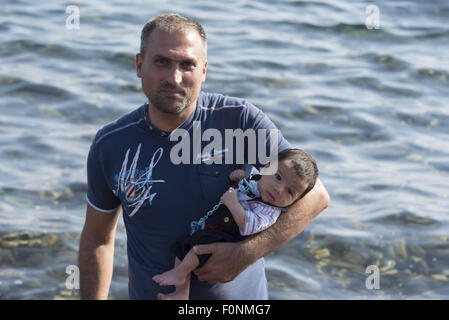 Lesbos, Griechenland. 19. August 2015. Ein syrischer Flüchtling hält ein Neugeborenes nach der Landung an einem Strand auf der Nordseite der Insel Lesbos. Mehr als 120.000 Flüchtlingen und Migranten haben aus der Türkei nach Griechenland bis Ende Juli 2015, nach des UN-Flüchtlingshilfswerks gekreuzt. Bildnachweis: Nikolas Georgiou/ZUMA Draht/Alamy Live-Nachrichten Stockfoto