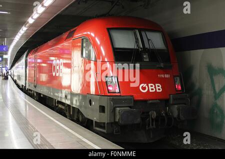 Rot e-Lok OBB Livree, mit Passagier Zug am Bahnsteig im Bahnhof Wien-Mitte in Österreich. Stockfoto