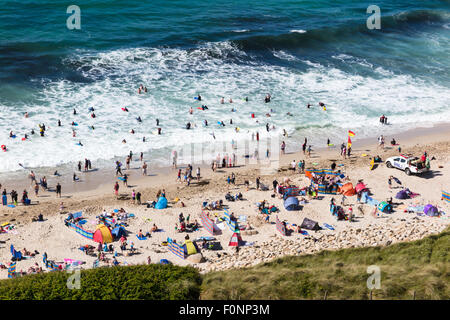 Einem anstrengenden Nachmittag auf Sennen Beach in Cornwall. Sonnenanbeter, Surfer und Body Boarder genießen Sie die Sonne und Wellen bei diesem pop Stockfoto