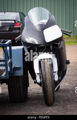 Ein moderner Rennsport Superbike lehnte sich gegen seine Anhänger im Fahrerlager auf einer Rennstrecke. Stockfoto