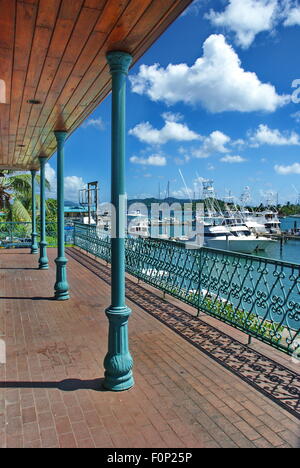 Ziegel Deck Gehweg mit rollbaren Eisenzaun mit Blick auf den Yachthafen in der Umgebung von Red Hook auf der Insel St. Thomas, USVI. Stockfoto