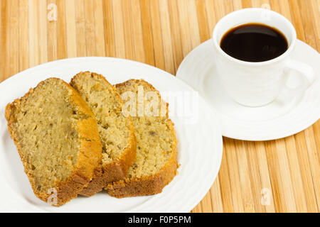 Eine Nahaufnahme der köstliche, hausgemachte, feucht, frisch gebackene Banane Brotscheiben auf einen Servierteller mit schwarzen Kaffee. Stockfoto