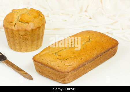 Eine Nahaufnahme der köstliche, hausgemachte, feucht, frisch gebackene Banane Brot auf eine weiße Tafel mit einem Sägemesser. Stockfoto