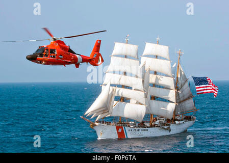 Die Coast Guard Cutter Eagle segelt in den Atlantischen Ozean, gefolgt von einem MH-65 Dolphin-Helikopter 30. Juli 2015. Die Bark Eagle ist die einzige aktive Segelschiff im Dienst der amerikanischen Streitkräfte den Auftrag. Stockfoto