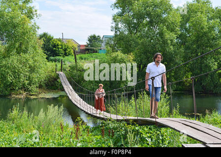 zwei Personen gehen auf einer Hängebrücke über den Fluss Stockfoto