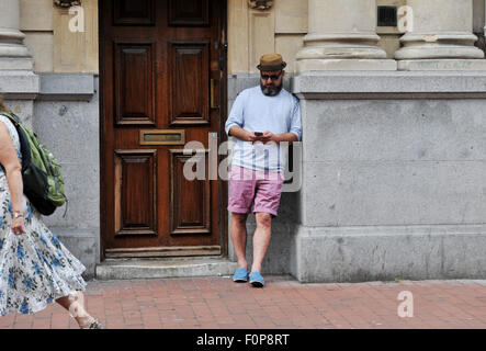 Junger Mann stehend in Straße Tür auf seine mobile smart Phone Brighton UK Stockfoto
