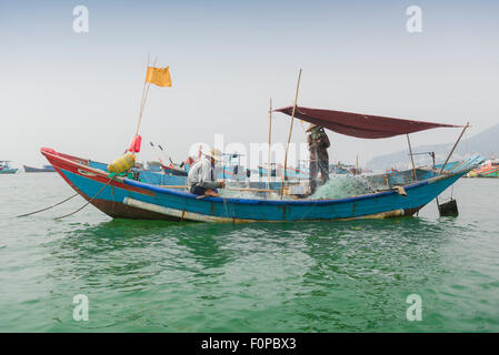 Vietnam Boot, vietnamesische Fischer Netze flicken an Bord ein Fischerboot im Hafen von Vung Tau, Vietnam verankern. Stockfoto