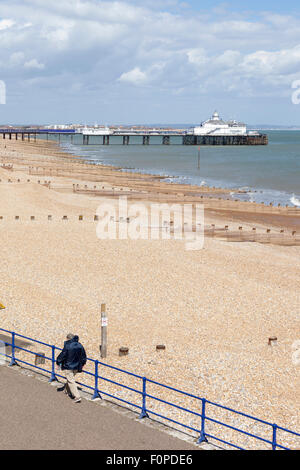 Der Pier und Strand und ein Mann zu Fuß entlang der Promenade, Eastbourne, East Sussex, England Stockfoto