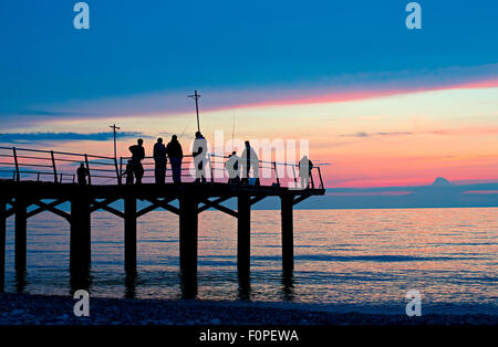 Gruppe von Fischern auf einem Pier bei Sonnenuntergang. Batumi, Georgien Stockfoto