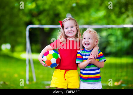 Zwei glückliche Kinder spielen Fußball im Freien im Schulhof. Kinder spielen Fußball. Aktiv Sport für Vorschulkind Stockfoto