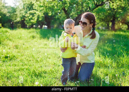 Kleinkind Jungen und seine Mutter macht mit vor wehen Löwenzahn Stockfoto