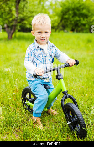 Glückliche kleine Junge Reiten Lernenden Fahrrad auf Rasen Stockfoto