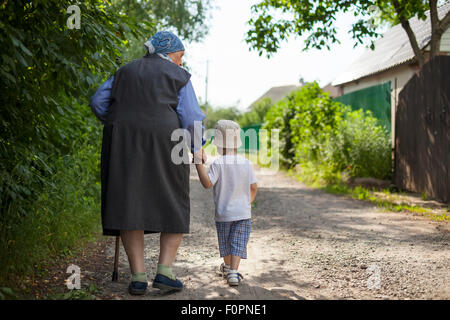 Große Großmutter und Kleinkind Jungen Hand in Hand beim gehen auf der Straße in Landschaft Stockfoto