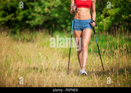 Fit junge Frau Wandern mit nordic walking-Stöcke im Sommer Stockfoto