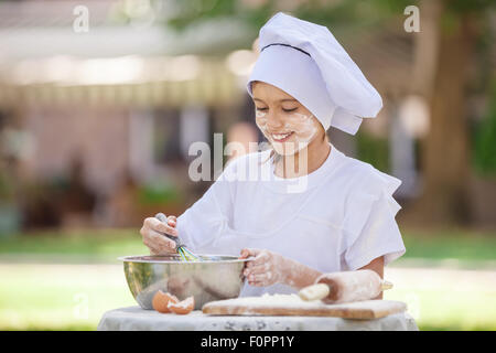 Glückliche kleine Chef Auspeitschen Eiern in einer Schüssel im freien Stockfoto