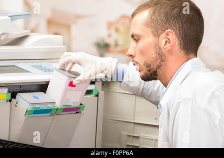 Closeup Aufnahme des jungen männlichen Techniker wechselnden Patrone Farbtoner in digitale Kopierer Maschine Stockfoto